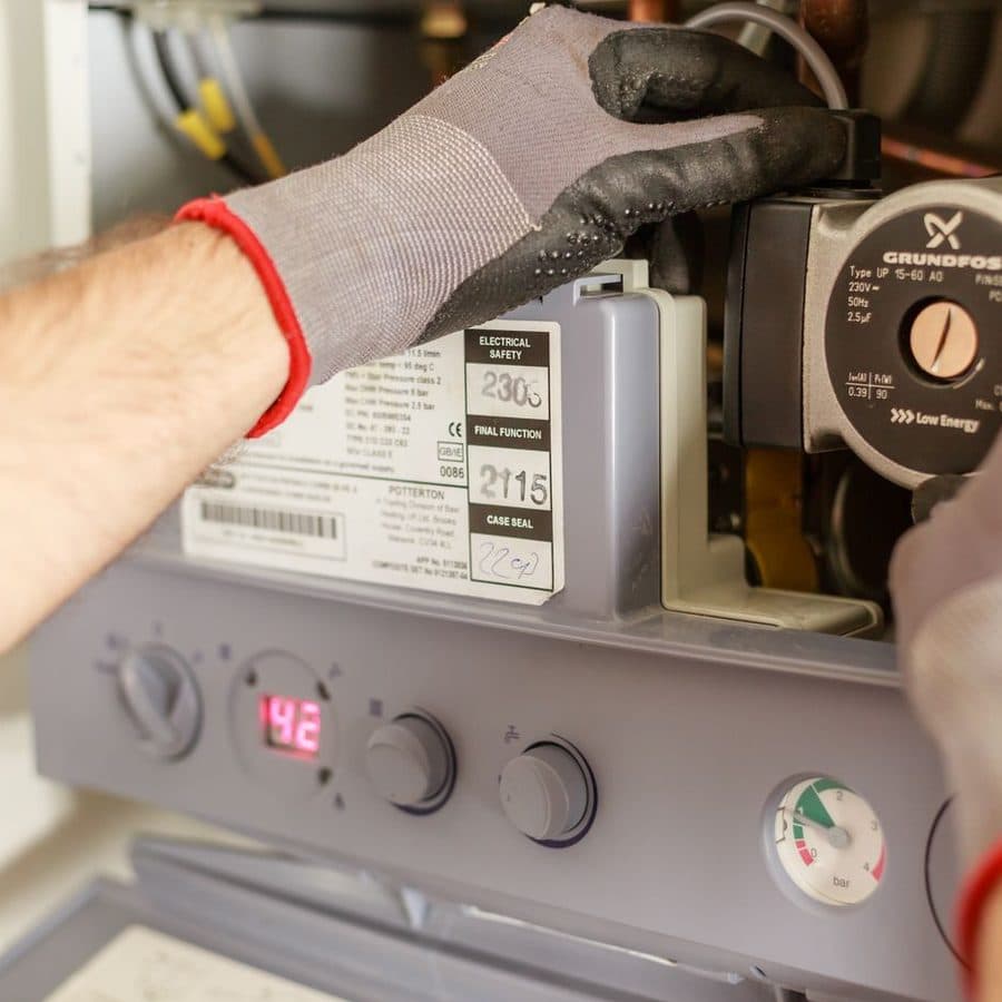 Manos con guante ajustando los controles de un calentador de pared